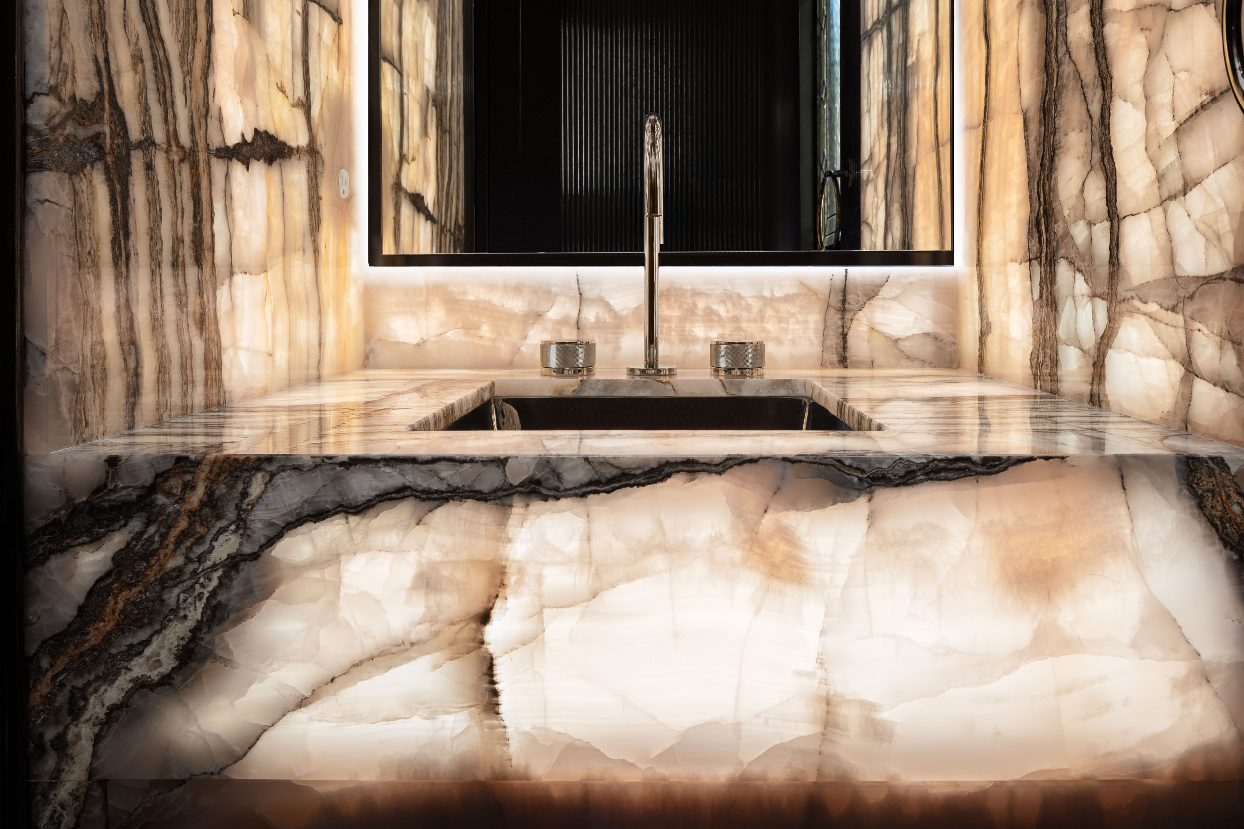 Glowing marble sink in black powder room