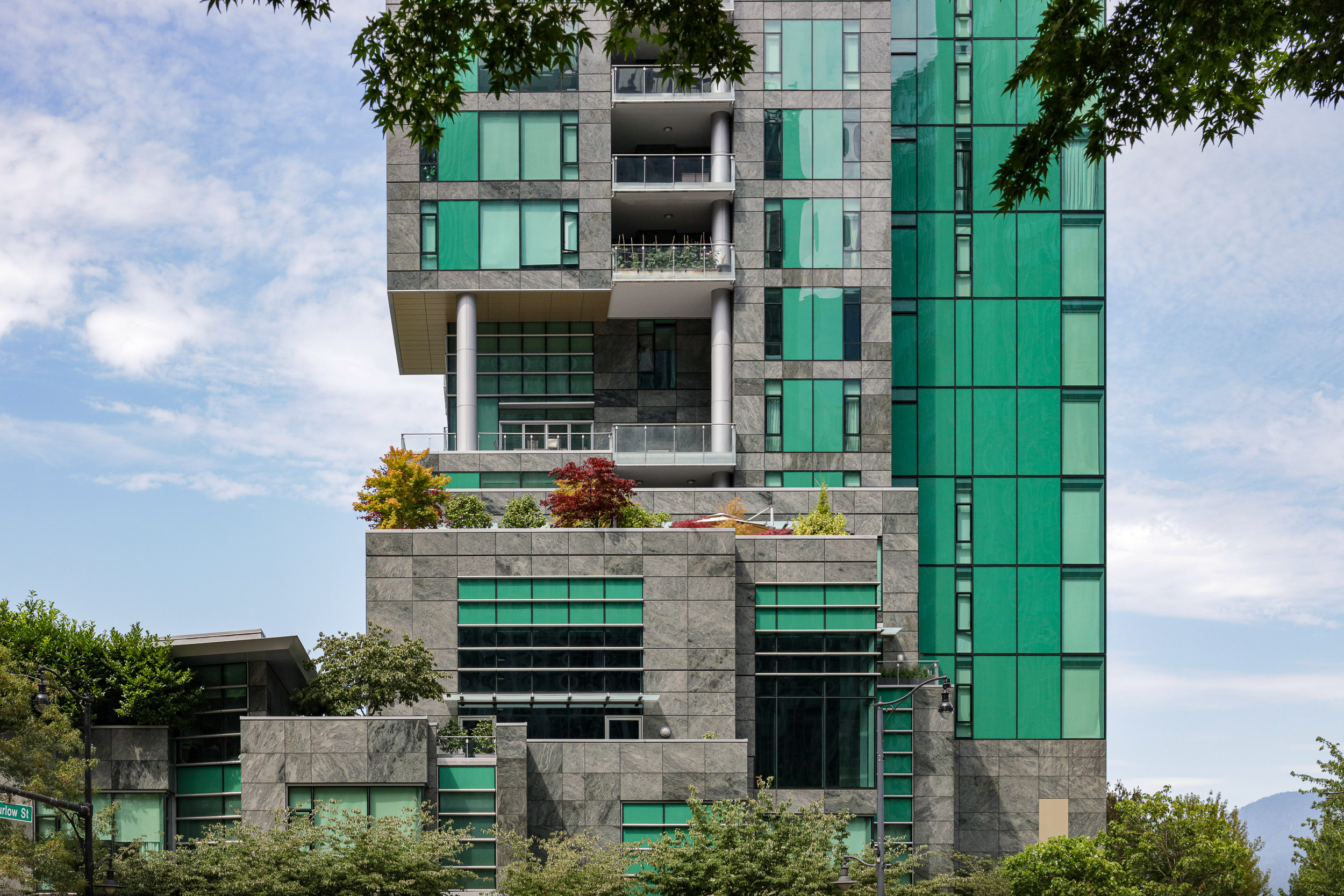 Green skyscraper surrounded by plantlife in urban setting